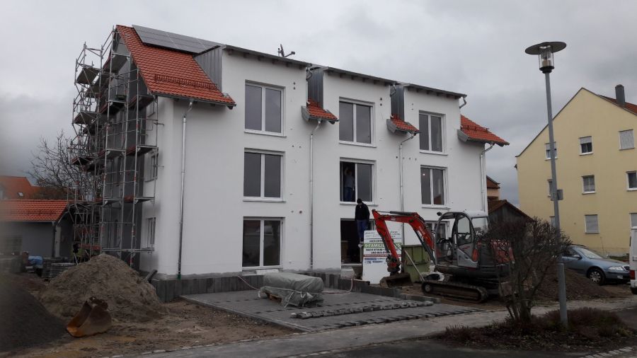 Dokončovaný bytový dům s hotovou fasádou a terénními úpravami